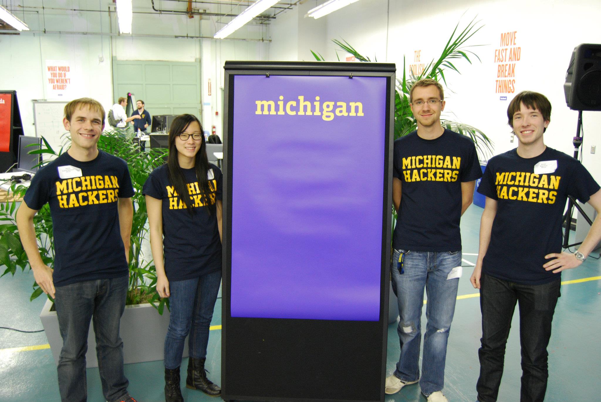 Photo of my other hackathon teammates and I standing around a Michigan sign at the Hackathon Finals